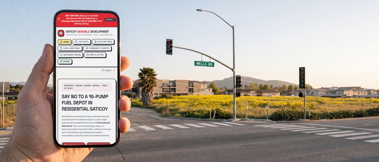 A hand holding a phone showing the Saticoy Sensible Development site and its headline opposing an 8-pump fuel depot, held up at the Wells Road intersection the campaign is about.