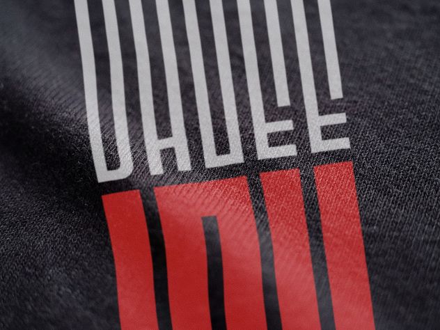Macro of the OhGee Ink logo printed on shirt fabric, the gray and red ink sitting on the weave.