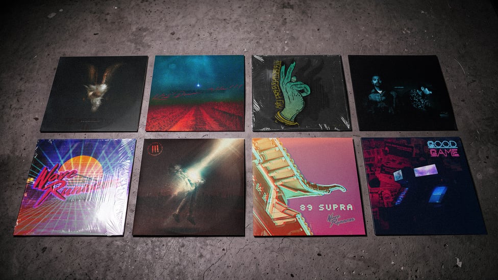 Eight album covers laid out in two rows on a concrete floor, each one a different world.